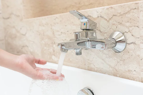 Жінка рука приймає ванну вдома перевірка температури, торкаючись w — стокове фото