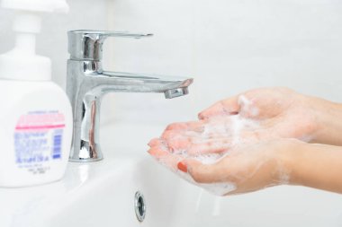 Kadın eli bembeyaz plastik pompa şişesine basar ve daha temiz köpük alır..
