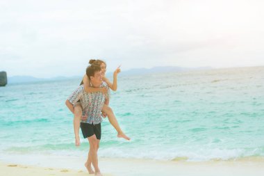 Mutlu genç Asyalı çift güneşli bir günde sahilde eğleniyor..