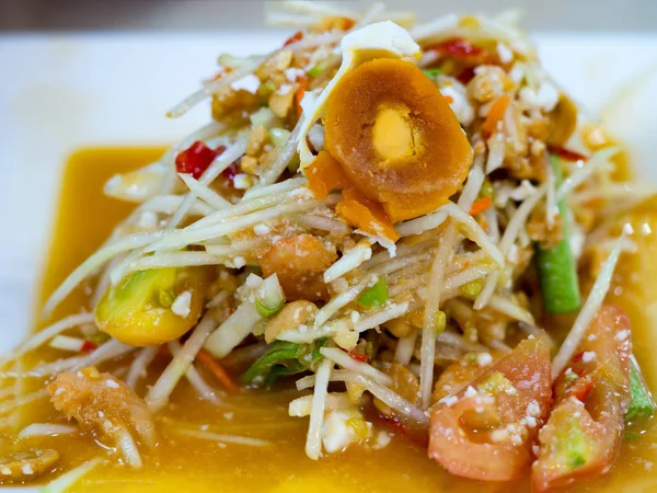 Зеленый салат папайи или Сом тум с сохраненным яйцом. Популярная тайская кухня. Пряный салат из измельченной незрелой папайи, нарезанные помидоры, сырая фасоль, арахис, сушеные мини-креветки и свежий чеснок . — стоковое фото