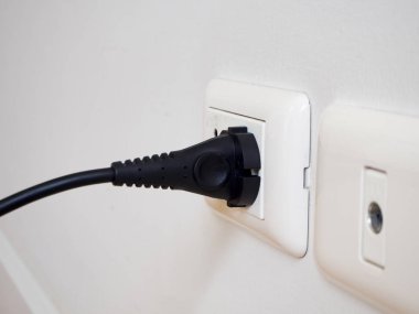 Siyah elektrik gücünden beyaz duvar beyaz soketi.