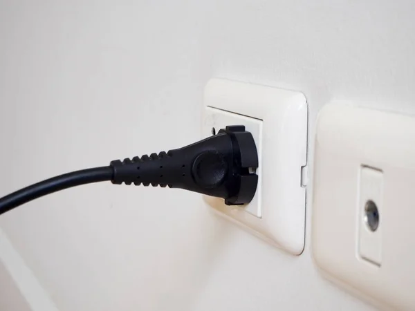 Siyah elektrik gücünden beyaz duvar beyaz soketi.