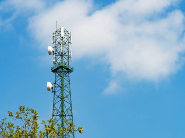 Mikrodalga bağlantısı olan yeşil kule ve televizyon vericisi antenleri mavi gökyüzü üzerinde telekomünikasyon direği antenleri.