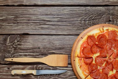 Ahşap bir masa üzerinde ev yapımı biberli pizza. Metin için yer.