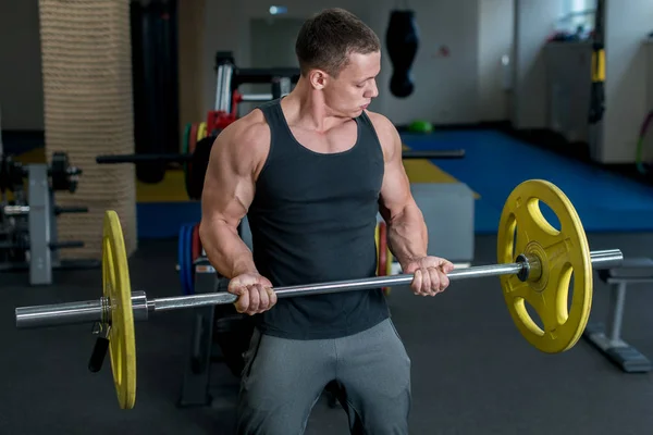 Concepto deportivo. Culturista en gimnasio haciendo ejercicio con pesas —  Fotos de Stock