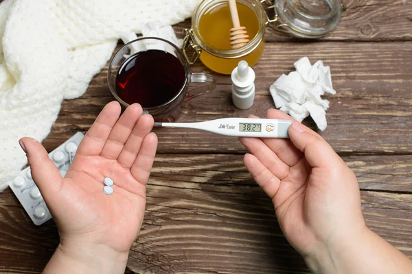 Tratamiento de la gripe y los resfriados. Manos femeninas con termómetro . — Foto de Stock