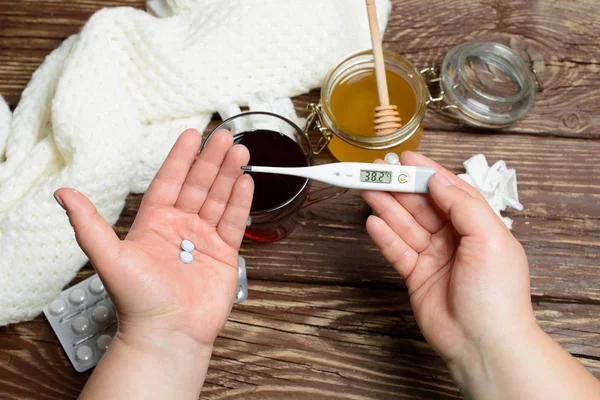 Tratamiento de la gripe y los resfriados. Té caliente, miel y medicinas en una mesa de madera . — Foto de Stock