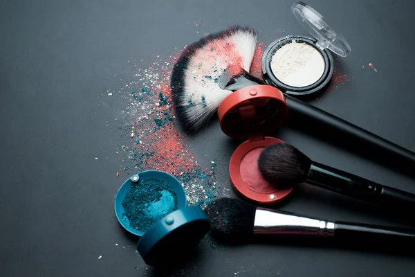 Set of cosmetics and makeup brushes on a black background