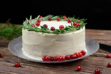 Ev yapımı kek krem peynir frosting ile dekore edilmiş biberiye ve ahşap bir masa üzerinde çilek ile