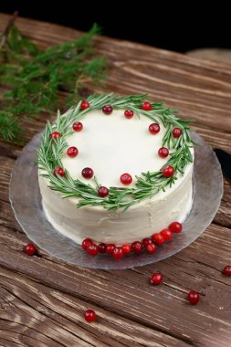 Ev yapımı kek krem peynir frosting ile dekore edilmiş biberiye ve ahşap bir masa üzerinde çilek ile