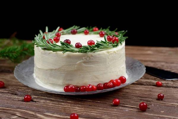 Ev yapımı kek krem peynir frosting ile dekore edilmiş biberiye ve ahşap bir masa üzerinde çilek ile