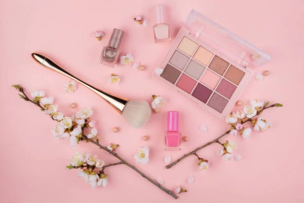 Kosmetika a Sakura větev na růžovém pozadí. Krása konceptu, byt ležel. — Stock fotografie