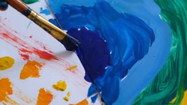 Boyalı fırçalar kullanarak renkli resimler çizen genç çocuklar eğlenceli yaratıcılığın tadını çıkarıyorlar.