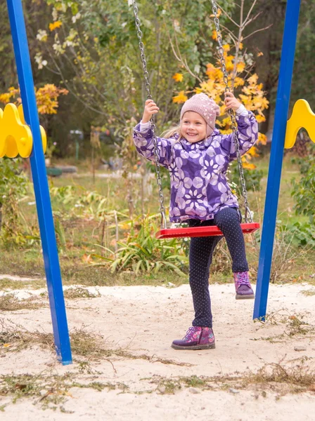 Küçük kız bahçede salıncak üzerinde tırmanma gülümseyen