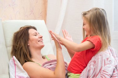 Küçük bir kız elleriyle oynayan genç kadın