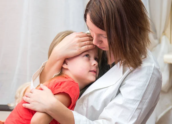 Doctor hugs and cuddle the little sick girl in bed