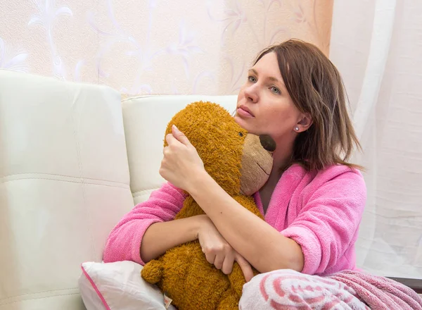 Young woman in bed hugging a teddy bear — Stock Photo, Image