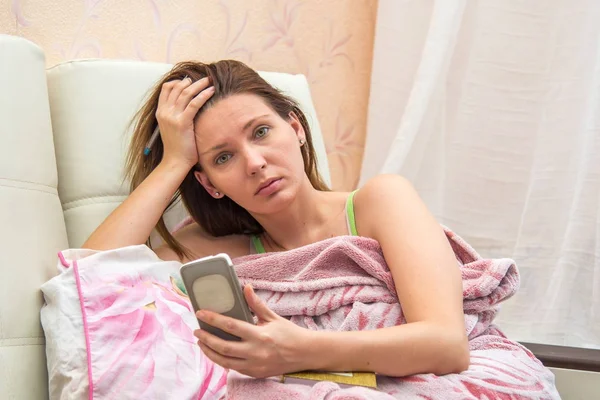 Young woman lying in bed with phone — Stock Photo, Image