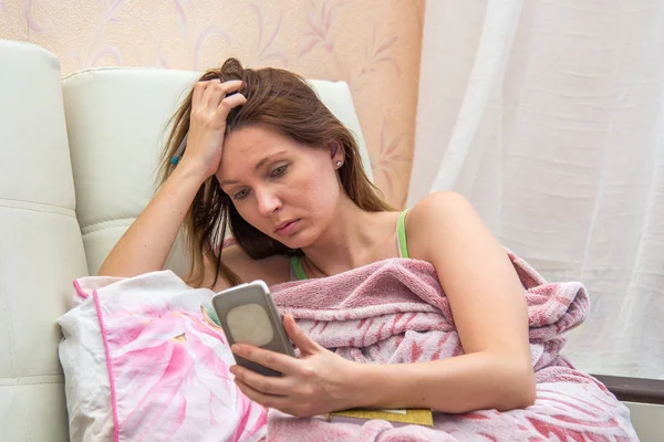 Young woman lying in bed with phone — Stock Photo, Image