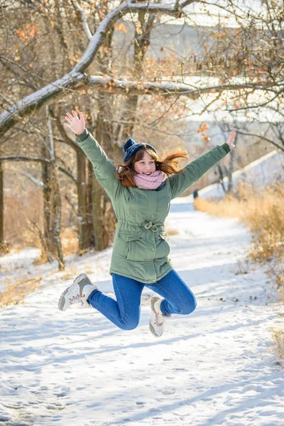 Veselá dívka, která skočila na zimní cestě v parku — Stock fotografie