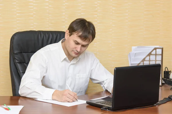 Человек в офисе стола пишет на бумаге Лицензионные Стоковые Изображения