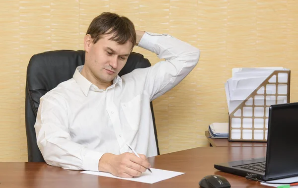 Der Mann am Schreibtisch in der Bürohand kratzt sich den Kopf — Stockfoto