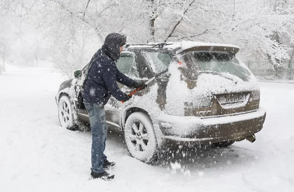 Volgograd. Rusya-Ocak, 16, 2017-bir adam bir kar yağışı sırasında arabasında kar temizler