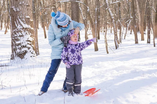 Máma narovná čepici holčička v zimě lese — Stock fotografie