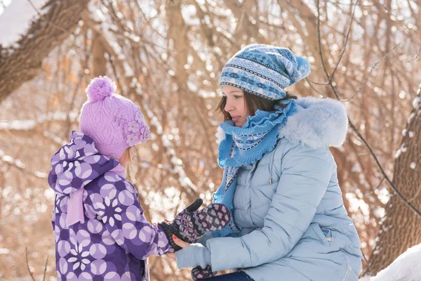 Matka klade na rukavice malá holčička v zimě lese — Stock fotografie