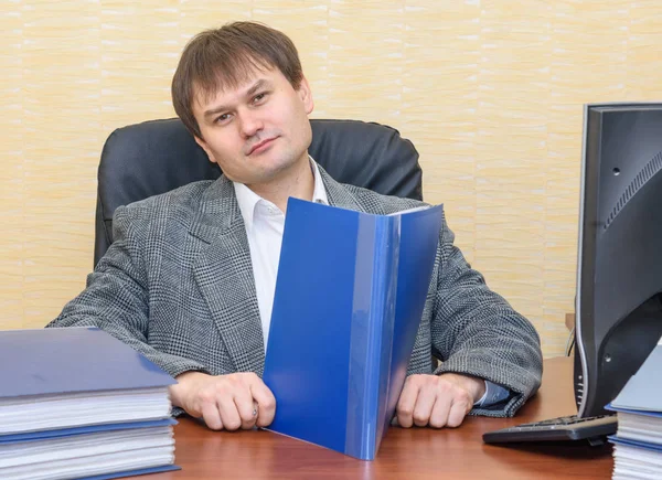 Bir klasör belgeler ile tutarak ofis masasındaki adam — Stok fotoğraf