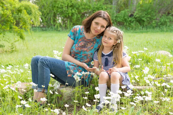 Mladá žena s 6 - ti letá holčička v kvetoucího parku na louce s bílými květy — Stock fotografie