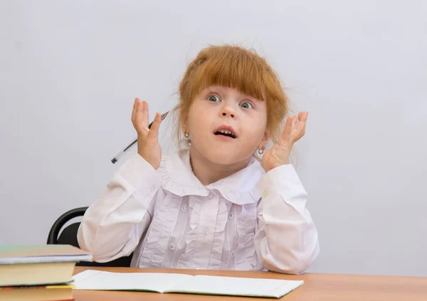 Menina na mesa olhos alargados, mãos para cima — Fotografia de Stock