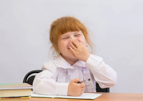 Menina na mesa alegremente ri, cobrindo a boca — Fotografia de Stock
