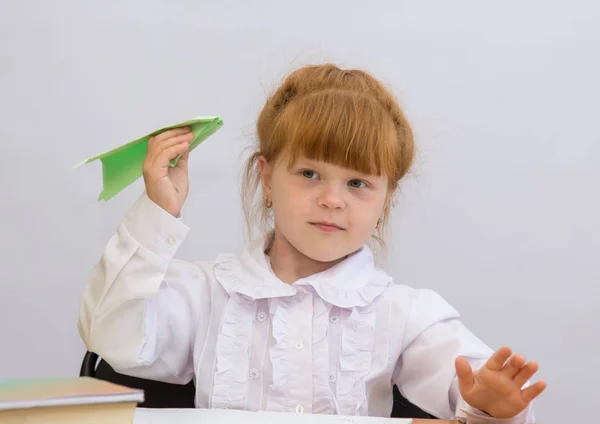 La niña en la mesa lanza un avión de papel —  Fotos de Stock