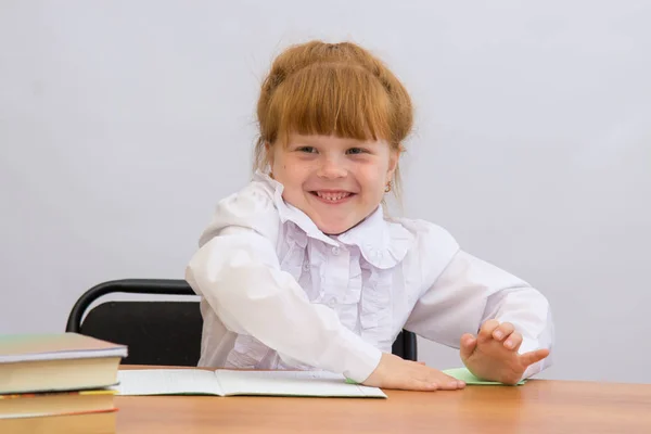 La niña en la mesa suaviza cuidadosamente el papel en el pliegue —  Fotos de Stock