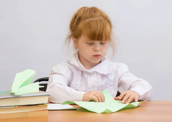 A menina na mesa com concentração faz Paper Airplane — Fotografia de Stock