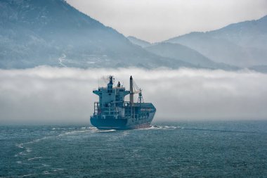Yalnız konteynır gemisi yoğun deniz sisi içinde hareket ediyor. Görüş mesafesi kısıtlı..