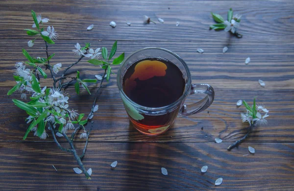 Ahşap yüzeyde yalan bir fincan ve kiraz dalında siyah çay. Vintage renk. Seçici odak