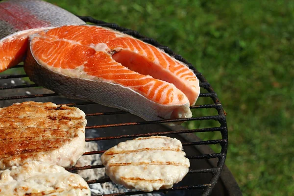 Kip of kalkoen hamburgers en zalm vissen op grill — Stockfoto