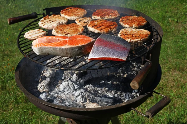 Chicken or turkey burgers and salmon fish on grill — Stock Photo, Image