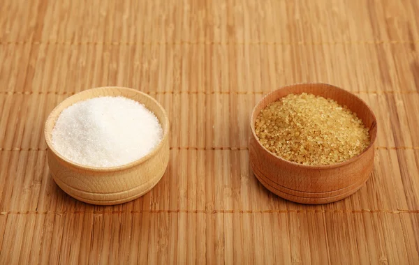 Açúcar de cana branco e marrom em tigelas de madeira no tapete — Fotografia de Stock