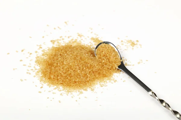 Lžíce a špetka hnědého třtinového cukru na bílém — Stock fotografie