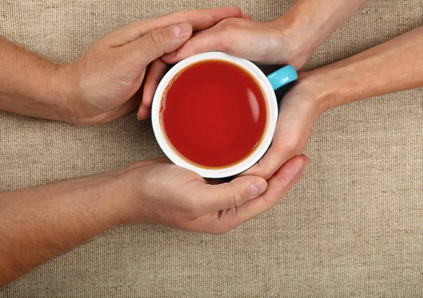 Férfi és a nő kezében tartja teljes fekete tea-cup — Stock Fotó