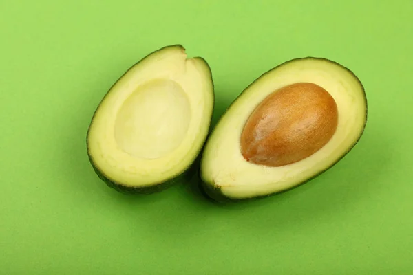 Two halves of fresh cut avocado on green paper
