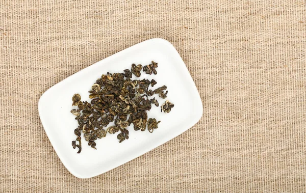 Piring daun teh hijau kering pada taplak meja kanvas — Stok Foto