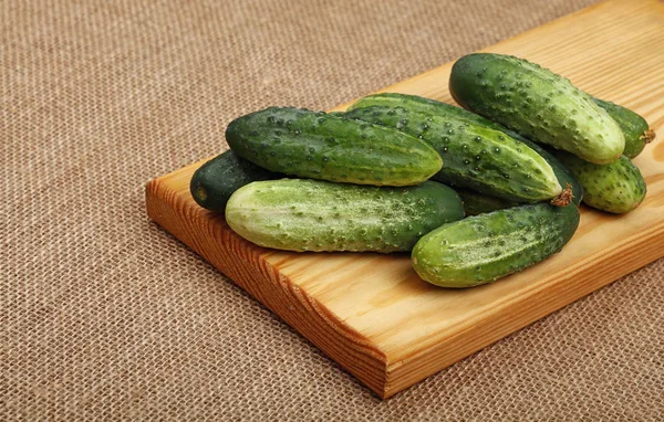 Cucumbers at wooden board on canvas — Stock Photo, Image