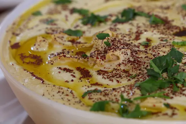 Hummus con aceite de oliva y perejil en un bol — Foto de Stock