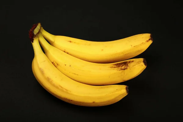 Kilka żółtych bananów na czarnym tle — Zdjęcie stockowe