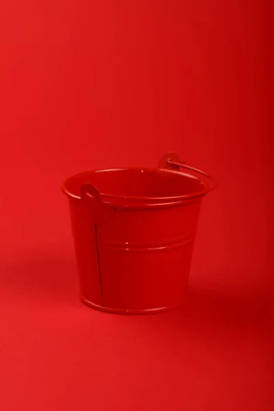 One small metal bucket on red background close up