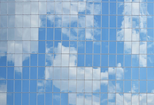 Облачное отражение неба в стекле бизнес-здания
